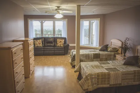 Bedroom with two beds, a wooden dresser, a sofa and a window