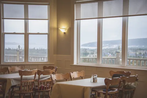 Dining tables and wooden chairs beside large windows