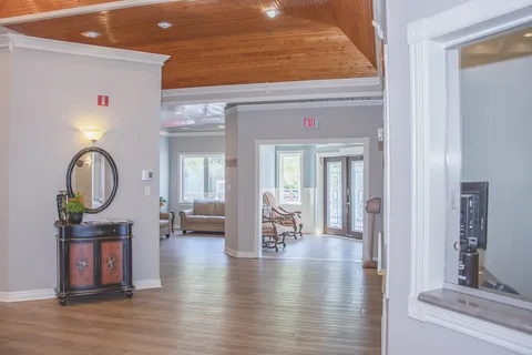 Interior with rocking chairs, a round mirror, a sideboard and large windows