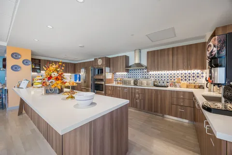 Kitchen with wooden cabinets, a large island, patterned tiles and a coffee dispenser