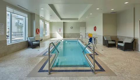 Indoor pool with handrails, chairs and large windows