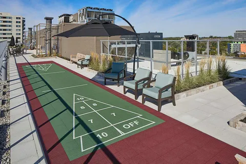 Rooftop terrace with a shuffleboard court, chairs and an umbrella