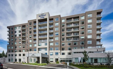 Multistorey brick building with balconies, a covered entrance and landscaped beds