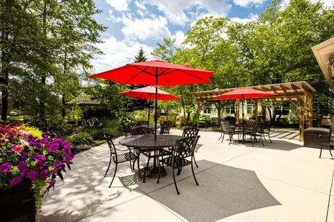 Patio with black tables, chairs, red umbrellas and flowering planters