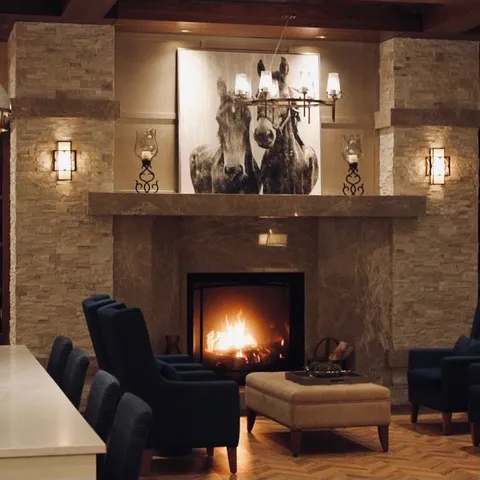 Lounge seating beside a stone fireplace and horse artwork.
