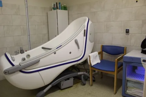 Bathing room with a raised accessible bathtub and chair.