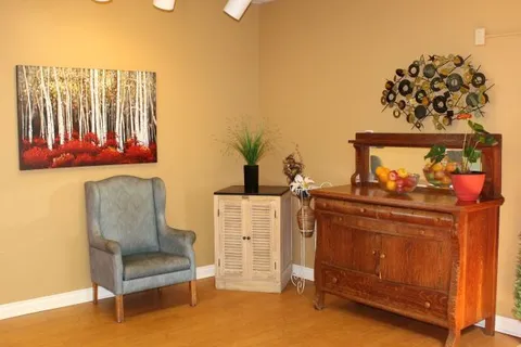 Sitting-room corner with an armchair, cabinet and wall artwork.