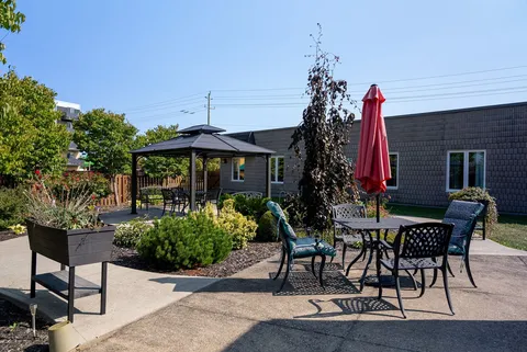 Outdoor patio with tables, chairs, umbrellas and planting beds.