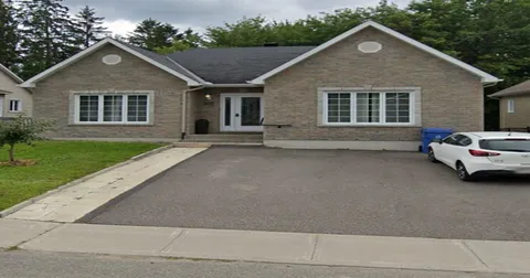 Residence exterior with a paved driveway, two front gables and a parked car.