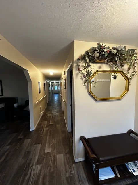 Hallway with wood-look flooring, wall pictures and a gold-framed mirror.