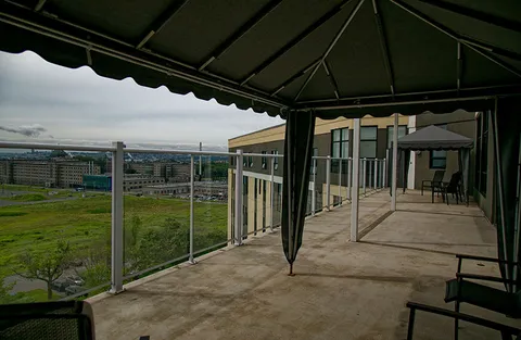 Rooftop terrace with gazebos, chairs and a glass railing overlooking the city