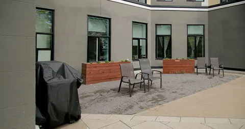 Courtyard seating with mesh chairs, wooden planters and a covered barbecue