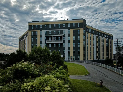 Multi-storey residence with balconies, a driveway and landscaped shrubs