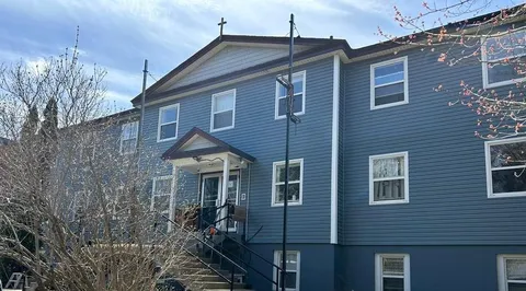 Blue building with white trim, peaked roofs and an entrance canopy