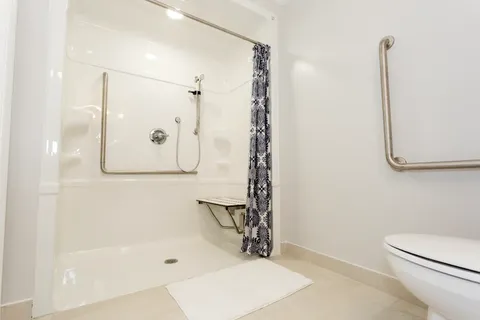 Bathroom with shower seat and grab rails.