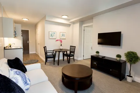 Suite living and dining area with sofa and wall-mounted television.