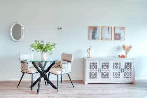 Suite dining area with a glass table, chairs and a sideboard.