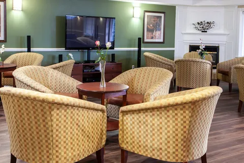 Lounge with wicker chairs, tables, a fireplace and television.