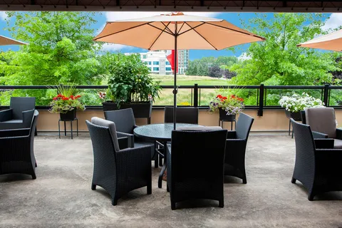 Patio with wicker seating, umbrella tables and planted beds.