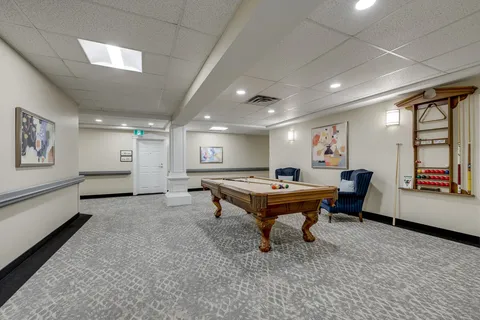 Billiards room with a pool table, blue chairs and cue racks