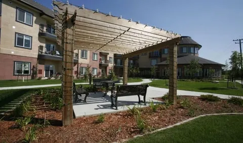 Patio table and chairs beneath a wooden pergola beside the residence
