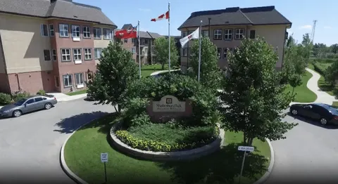Residence buildings, flags and trees around a planted traffic island