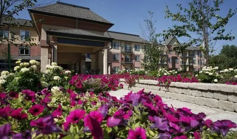 Building entrance behind raised beds of pink and white flowers