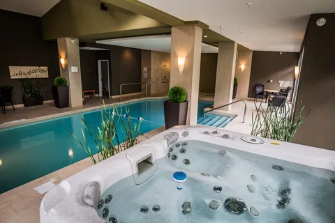 Hot tub beside an indoor pool, potted plants and seating