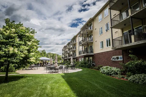Rear of the residence beside a lawn, trees and outdoor tables