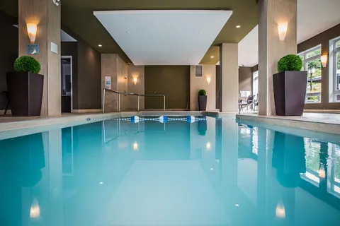 Indoor pool with tall columns, potted plants and large windows