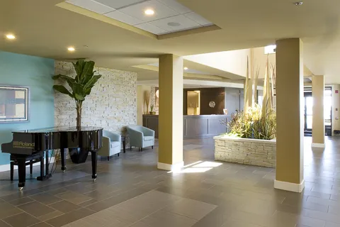 Piano and armchairs beside a planted bed and stone-clad walls