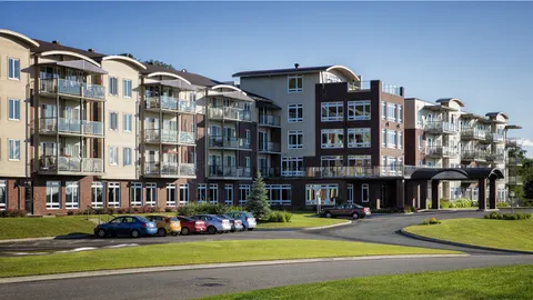 Residence exterior with curved balcony roofs, a lawn and parked cars