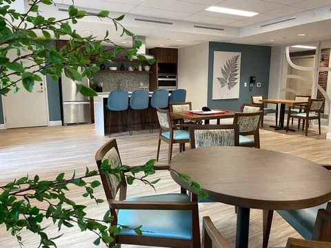 Tables and chairs beside a kitchen counter with blue stools