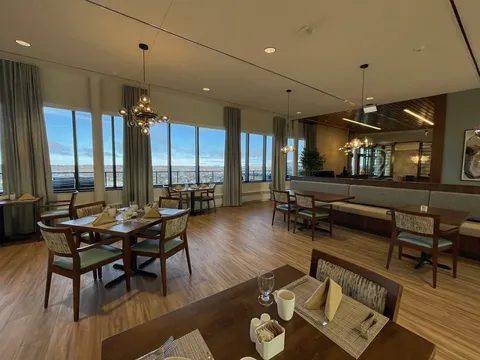Dining area with set tables, wooden chairs and large windows