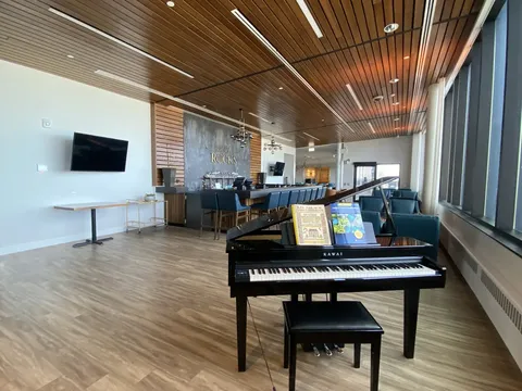 Long room with a grand piano, seating and windows along one wall