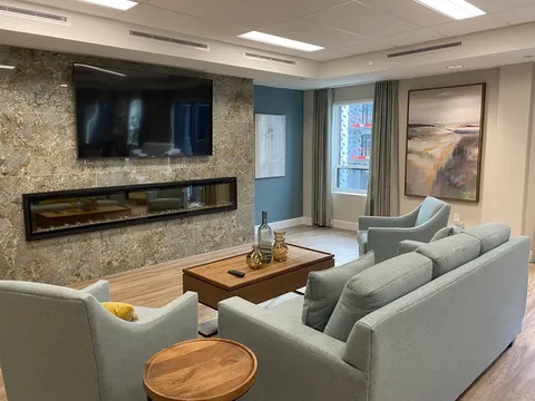 Lounge with grey seating facing a television and linear fireplace