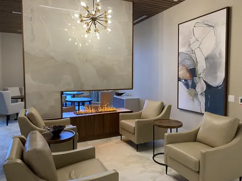 Armchairs around a modern fireplace beneath a chandelier