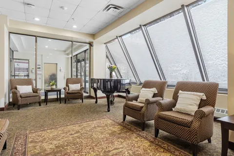 Lounge with upholstered armchairs, a grand piano and tall windows