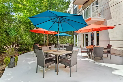 Patio with tables and colourful umbrellas beside the residence building