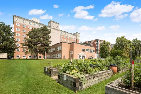 Brick residence building beside a lawn and raised garden beds