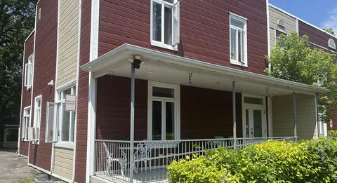 Red and cream residence with a covered porch and white railings