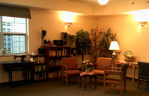 Library seating with bookshelves, plants and a window.