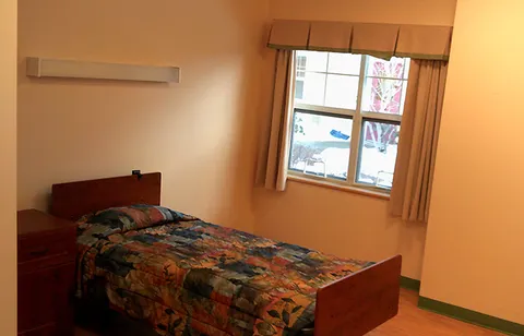 Suite bedroom with a bed, air conditioner and window.