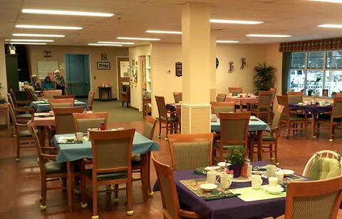 Dining room with set tables, wooden chairs and large windows.