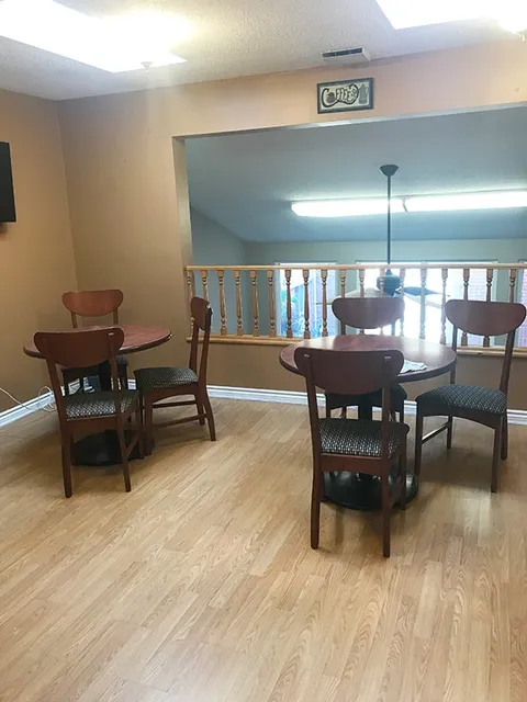 Room with round tables, wooden chairs, a wooden railing and a Coffee sign
