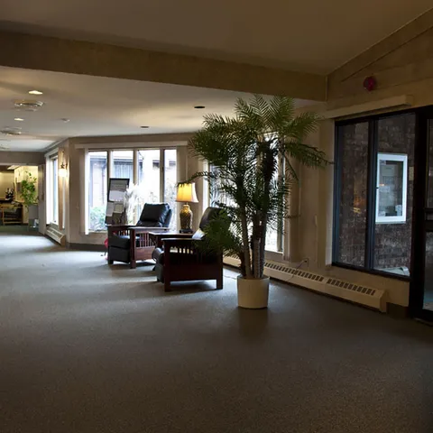 Entrance hall with armchairs, large windows and a potted palm