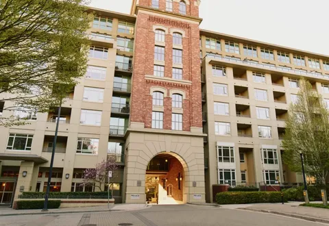 Multi-storey building with balconies and a red brick tower over an arched entrance