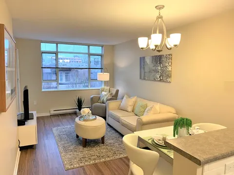 Sitting area with a sofa, armchair and small dining table beside kitchen counters