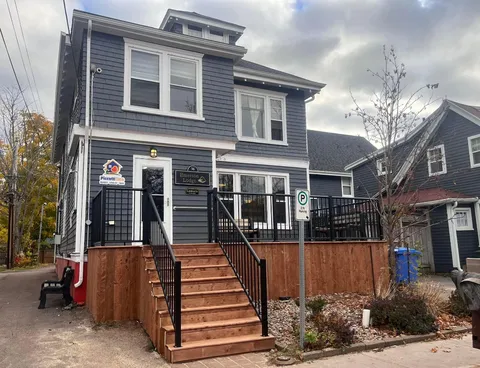 Grey house with a porch, entrance steps, an access ramp and flower beds