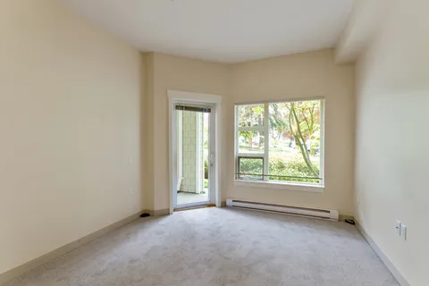 Empty carpeted room with a glass balcony door and a large window
